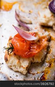 Toasted bread with crushed baked tomato on metal baking tray, selective focus