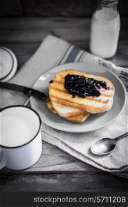 Toasted bread with jam and milk on wooden background