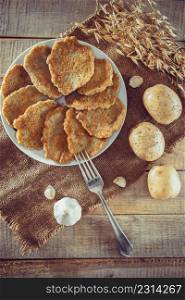 Toasted potato pancakes on a light linen background, flatlay. Potato pancakes on a plate and fork on linen background