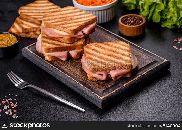 Toasted sandwiches with salami and melted cheese on black background. Delicious fresh toast grill with cheese and ham. Sandwiches, quick snack