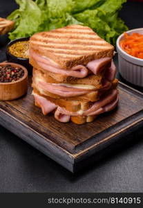 Toasted sandwiches with salami and melted cheese on black background. Delicious fresh toast grill with cheese and ham. Sandwiches, quick snack