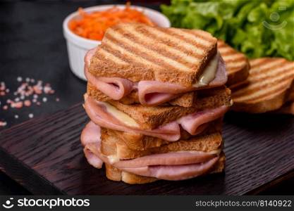Toasted sandwiches with salami and melted cheese on black background. Delicious fresh toast grill with cheese and ham. Sandwiches, quick snack