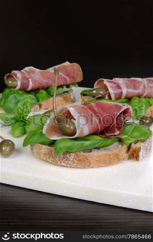Toasted slices of jamon jerked pork leg with capers and basil