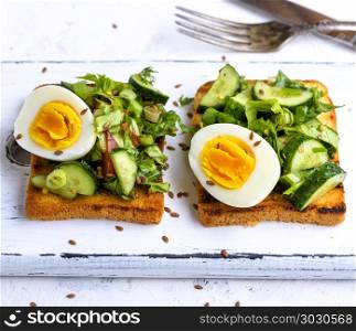 toasted square pieces of bread from white wheat flour with boiled egg, cucumber and green spinach leaves , close up. toasted square pieces of bread from white wheat flour with boile