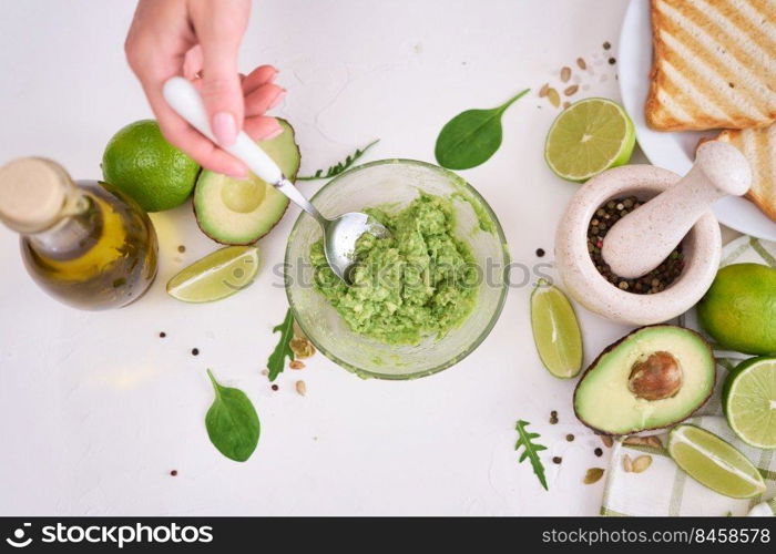 Toasts preparation - Mashed avocados in a glass bowl.. Toasts preparation - Mashed avocados in a glass bowl