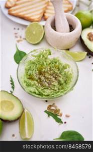 Toasts preparation - Mashed avocados in a glass bowl.. Toasts preparation - Mashed avocados in a glass bowl