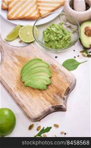 Toasts preparation - sliced peeled and mashed avocados and grilled toast bread.. Toasts preparation - sliced peeled and mashed avocados and grilled toast bread