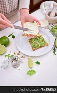 Toasts preparation - woman smearing cream cheese on a toasted bread.. Toasts preparation - woman smearing cream cheese on a toasted bread