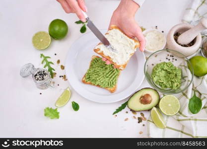 Toasts preparation - woman smearing cream cheese on a toasted bread.. Toasts preparation - woman smearing cream cheese on a toasted bread