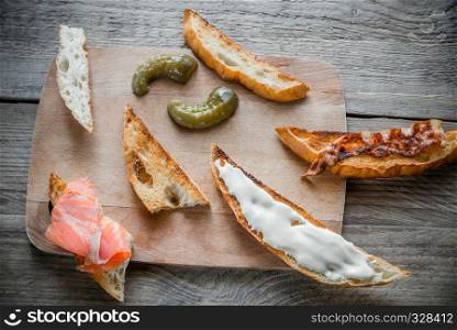 Toasts with different toppings on the wooden board