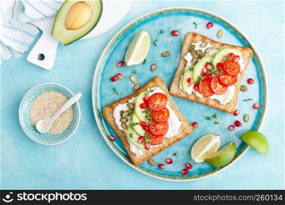 Toasts with feta cheese, tomatoes, avocado, pomegranate, pumpkin seeds and flaxseed sprouts. Diet breakfast. Delicious and healthy food. Flat lay. Top view