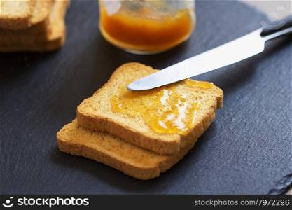 Toasts with jam over black stone background, strict DOF, horizontal image