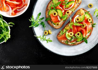 Toasts with salted salmon, arugula, green olives and cucumber, copy space, top down view