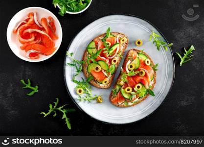 Toasts with salted salmon, arugula, green olives and cucumber, top down view