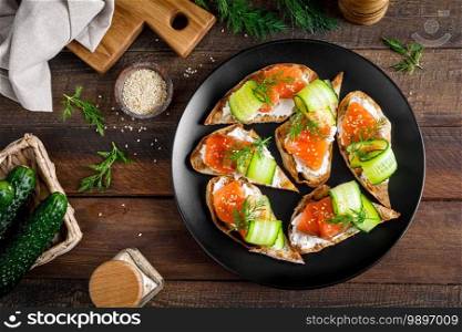 Toasts with salted salmon fish, ricotta cheese, fresh cucumber and ciabatta bread