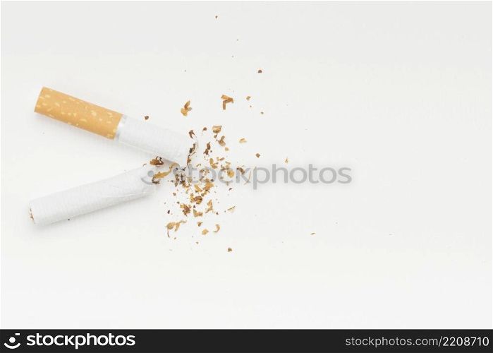 tobacco coming from broke cigarette against white backdrop