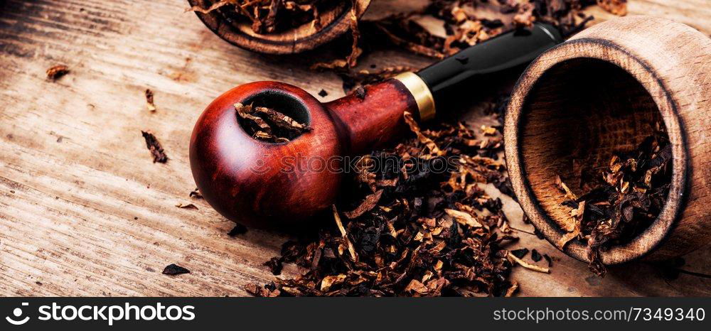 Tobacco pipe or smoking pipe on a wooden table. Smoking pipe and tobacco