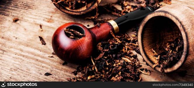 Tobacco pipe or smoking pipe on a wooden table. Smoking pipe and tobacco