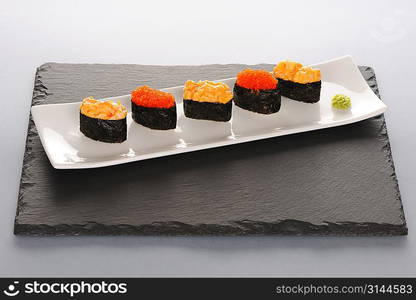 Tobiko and spice sushi on a slate plate