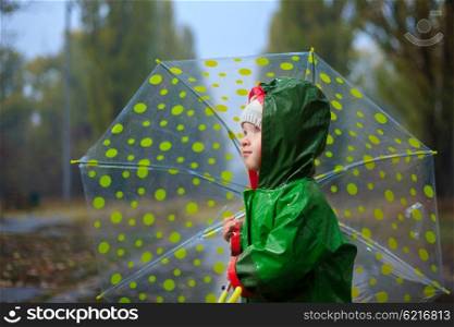 Toddler and umbrella in autumn rainy park