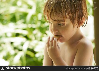 Toddler boy eating cookie outdoors