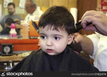 Toddler boy getting his hair cut at the barbershop.