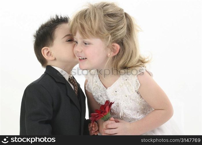 Toddler boy giving pretty 4 year old girl a kiss on the cheek.