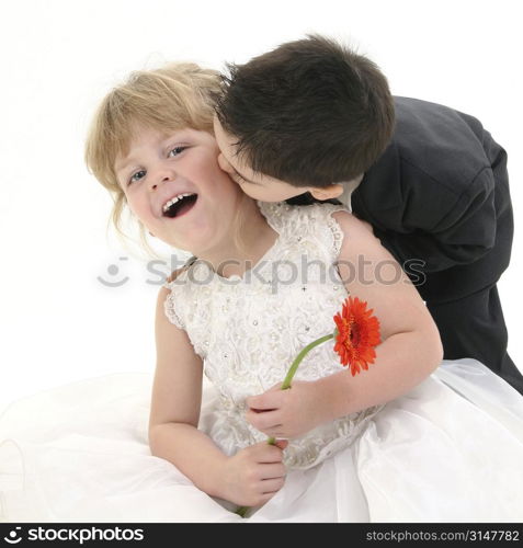 Toddler boy giving young girl a kiss on the cheek. Shot in studio over white