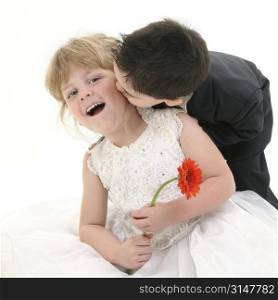 Toddler boy giving young girl a kiss on the cheek. Shot in studio over white