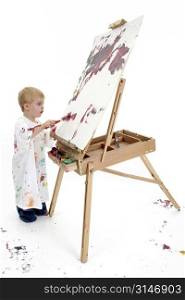 Toddler boy in big white shirt covered in paint at easel. American blonde caucasian boy. Shot over white background.