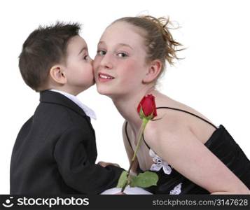 Toddler boy in suit kissing a beautiful teen girl on the cheek.