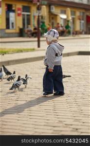 Toddler boy outdoor play with flock of feeding pigeons