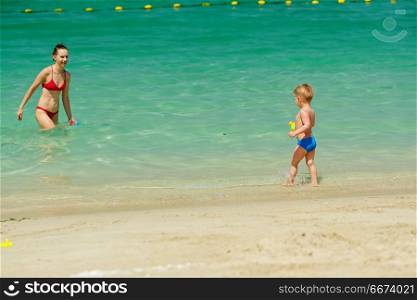 Toddler boy playing on beach with mother . Two year old toddler boy playing on beach with mother