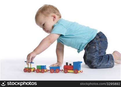 Toddler boy playing with a wooden toy train on the floor