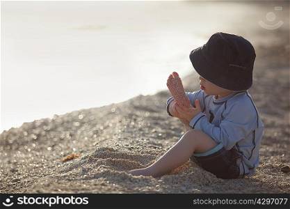 Toddler boy playing with sand on beach