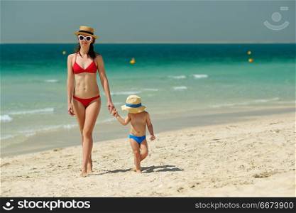 Toddler boy walking on beach with mother . Two year old toddler boy walking on beach with mother
