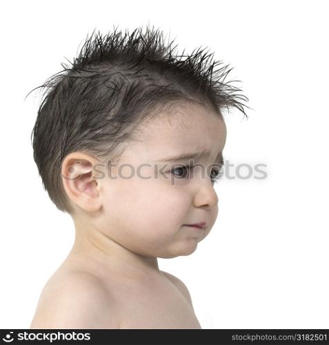 Toddler boy with upset expression, no shirt, spiked hair over white.