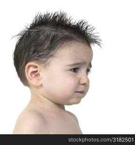 Toddler boy with upset expression, no shirt, spiked hair over white.
