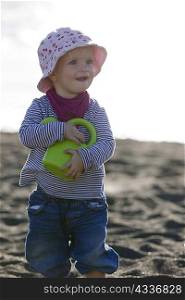 Toddler carrying watering can on beach