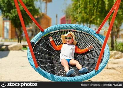 Toddler child swinging on beach. Portrait of toddler child swinging on beach. Kid playing outside.