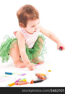 Toddler girl draws with wax crayons on the paper