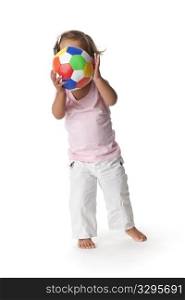 Toddler girl hiding behind a colored ball on white background