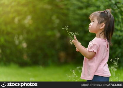 toddler girl playing grass flower in a field