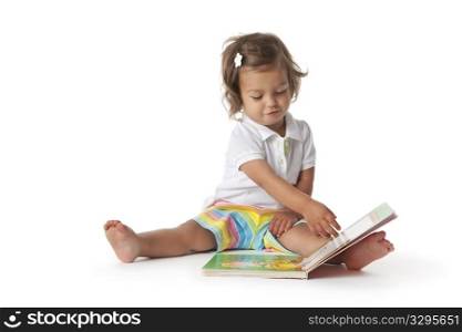 Toddler girl pretends to read a book on white background
