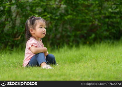 toddler girl sitting in grass field