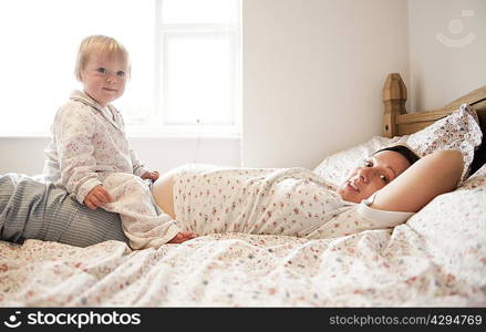 Toddler girl sitting with mother in bed