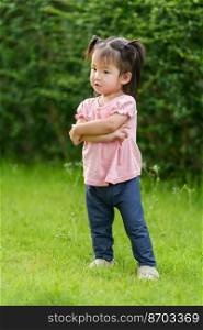 toddler girl with arms crossed in grass field