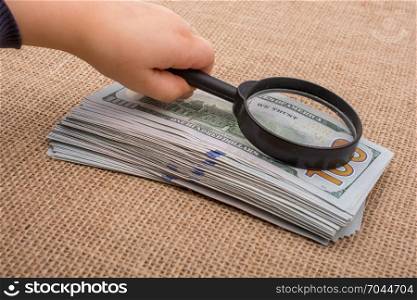 Toddler holding a magnifying glass over the banknote bundle of US dollar