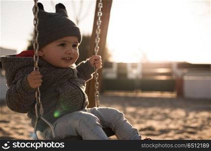 Toddler on a swing seat. Toddler having fun on a swing seat - Sunset Light