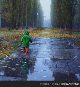 Toddler running in autumn rainy park